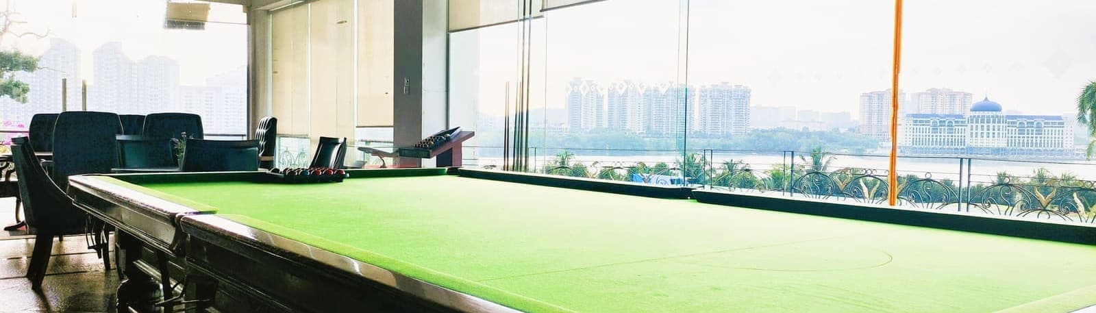 A billiards table beside floor-to-ceiling windows overlooking the lake and city skyline