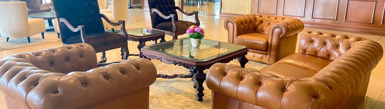 A seating area with leather chesterfield sofas and armchairs around a carved coffee table