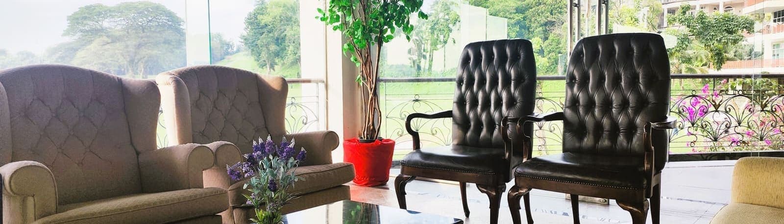 A glass-walled lounge with armchairs overlooking a landscaped balcony