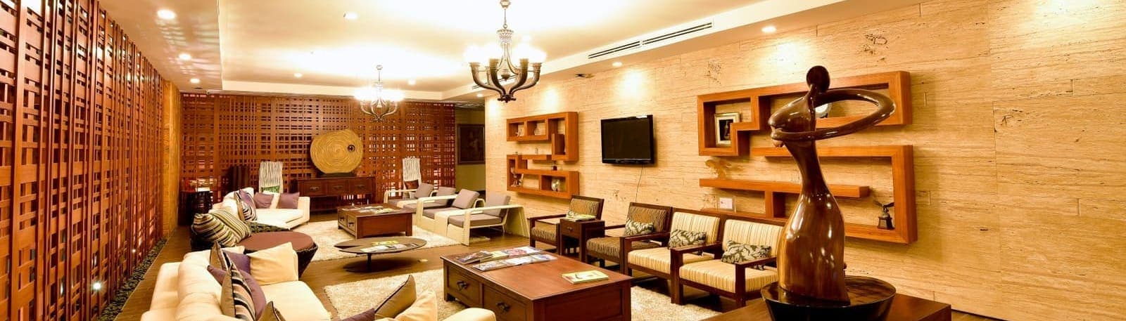 A lounge seating area with carved wood-lattice screens, sofas and a decorative wood shelving display