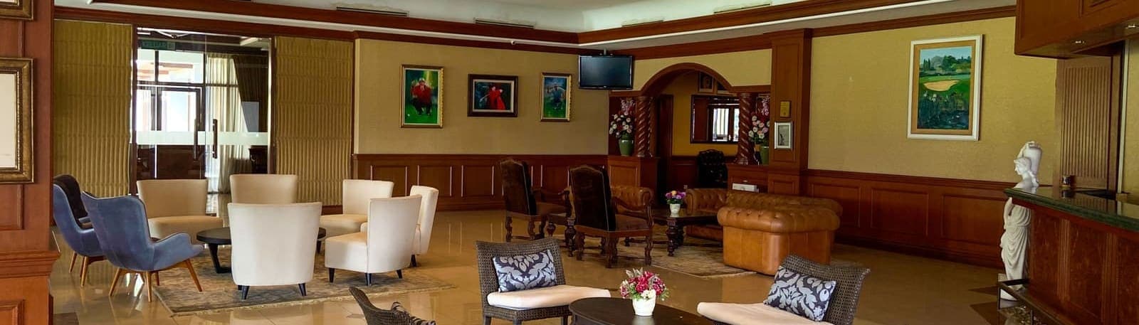 A members' lounge with armchairs, a leather sofa and golf-themed artwork on the walls
