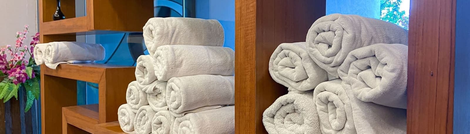 Stacks of neatly rolled towels on wooden shelving