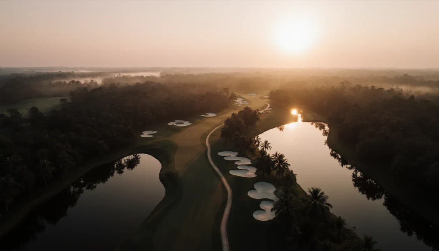 Aerial view of the course between the lake and the jungle at dusk