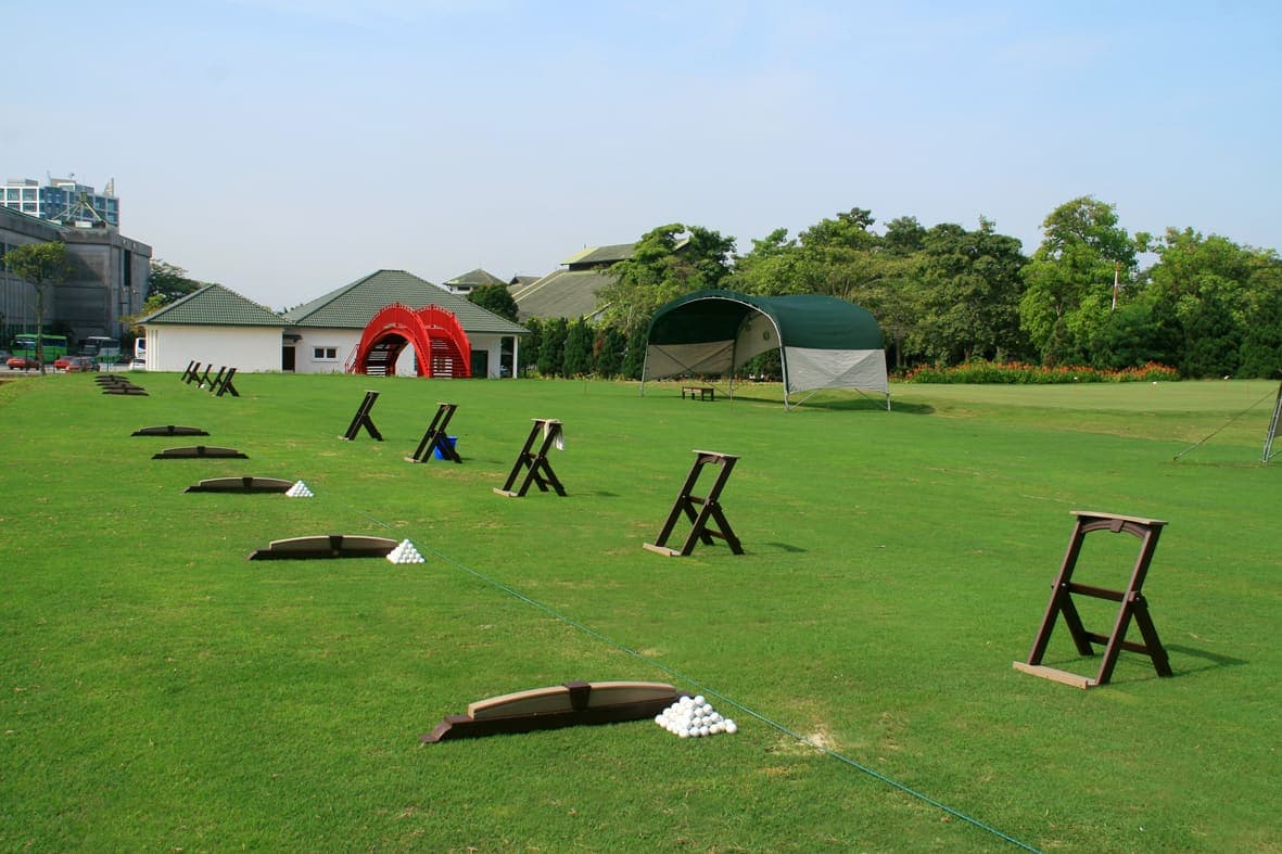 The driving range's practice mats and ball baskets, with the clubhouse in the background