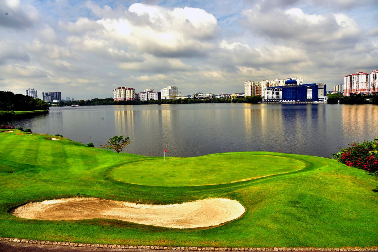 A green and greenside bunker overlooking the lake, with the Kuala Lumpur skyline in the distance