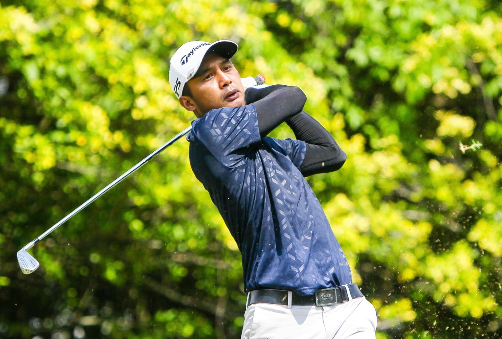 A golfer completing a swing, club raised over the shoulder