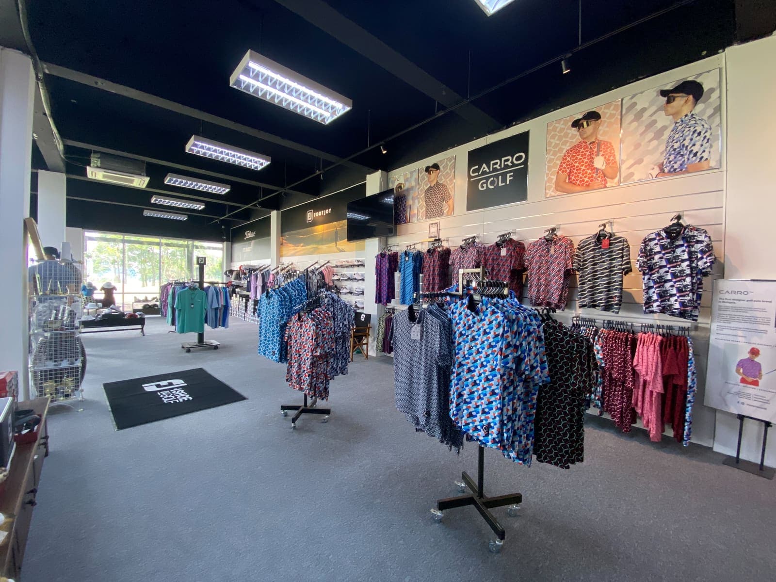 Golf apparel racks and accessories displayed inside the pro shop, with FootJoy and Titleist branding on the walls
